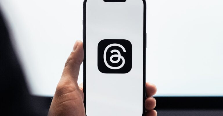 Close-up of a person holding a smartphone displaying Meta's threads logo.